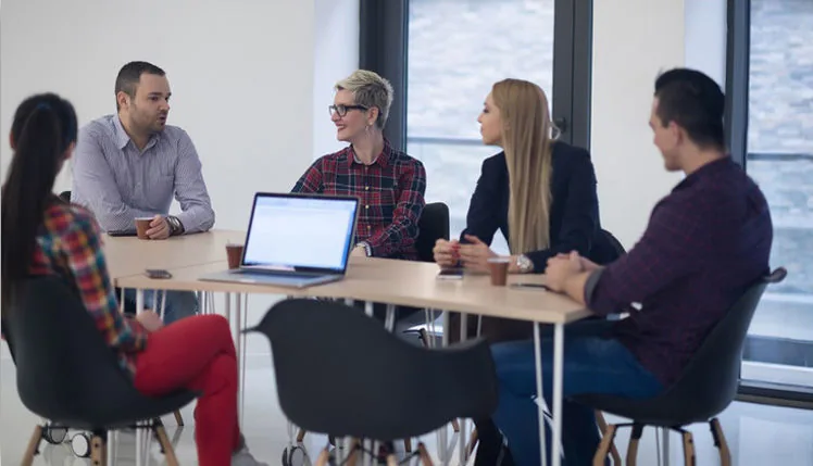 Equipe reunida em torno de uma mesa de trabalho